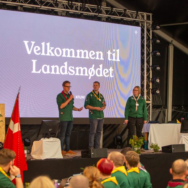 To spejderledere viser en færdselstavle for en gruppe børn